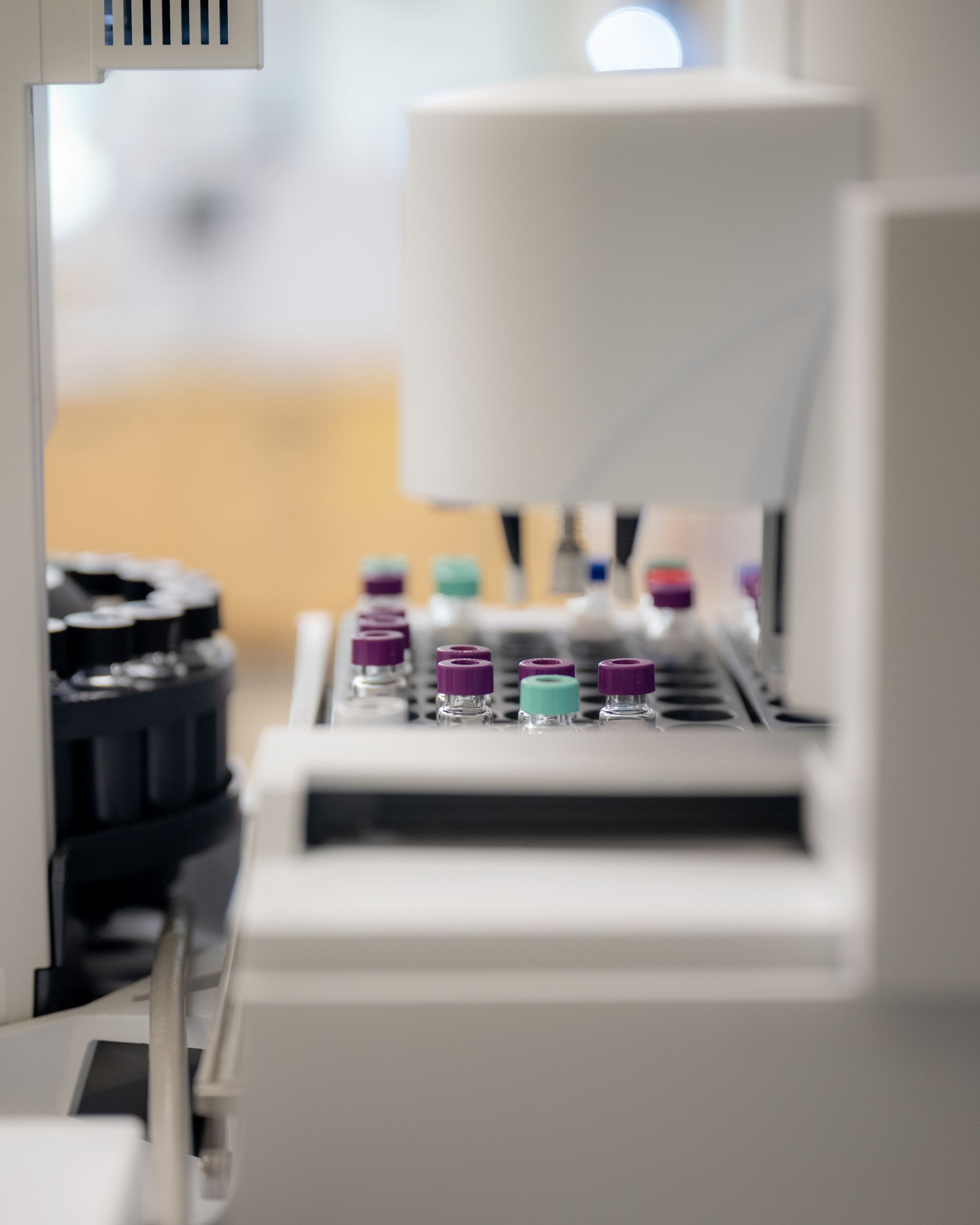 A photo shows a machine that has a number of vials in it with purple and pale green caps. 