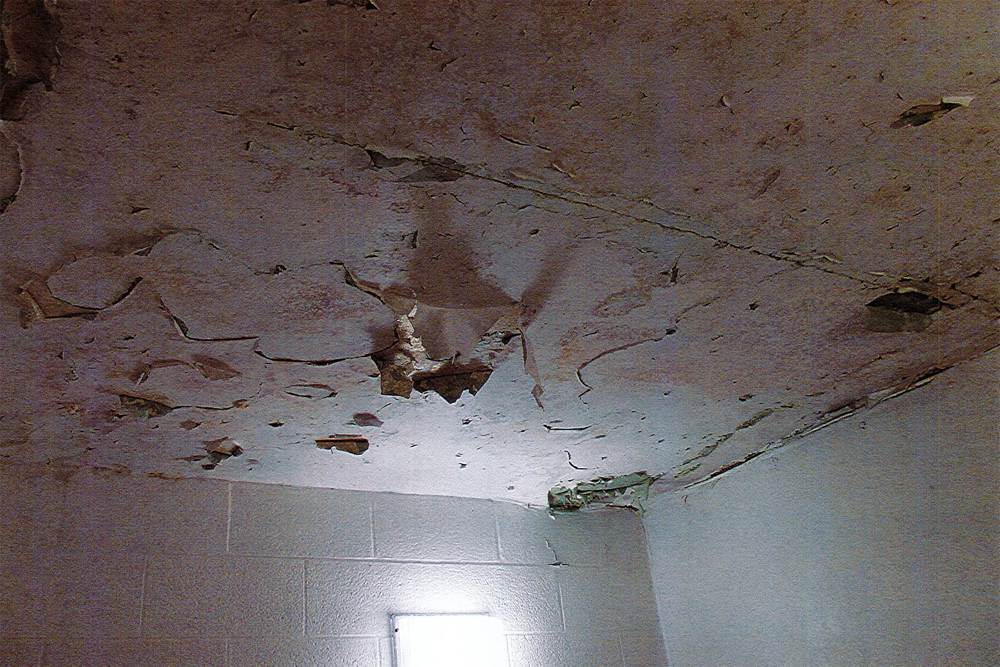 A photo shows a ceiling marred with peeling paint. 