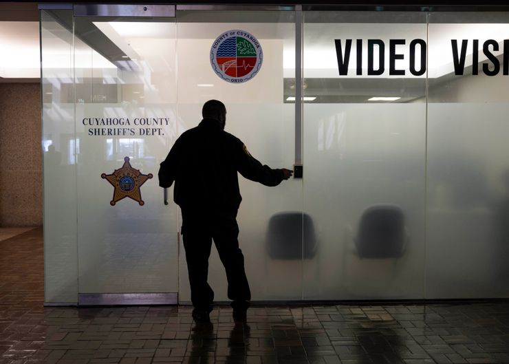 A man stands in silhouette in front of glass doors of a video visitation area at the Cuyahoga County Sheriff’s Department.  