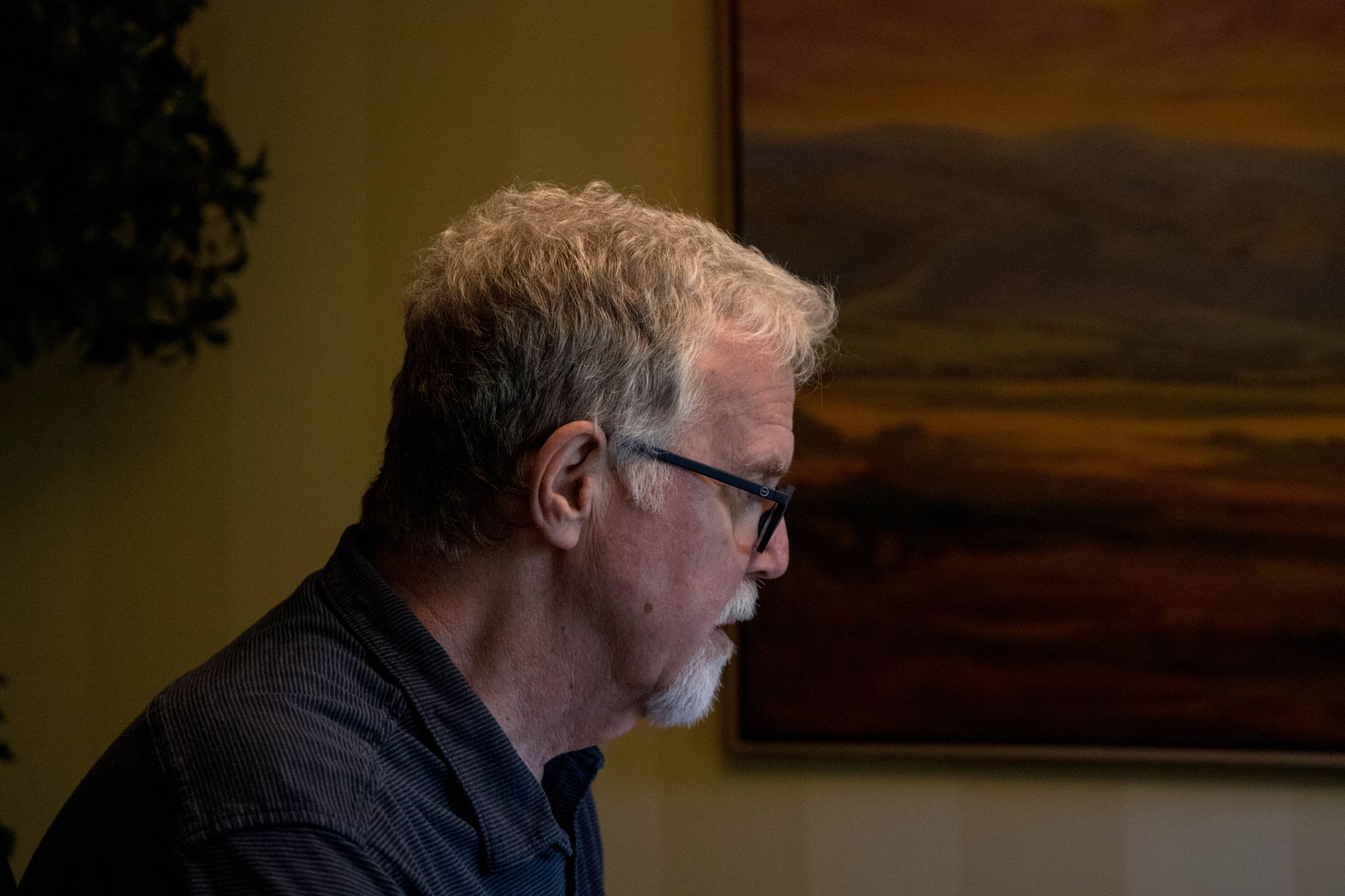 Belzley, a White man with a goatee and dark-rimmed glasses, faces to the right while sitting at his desk.