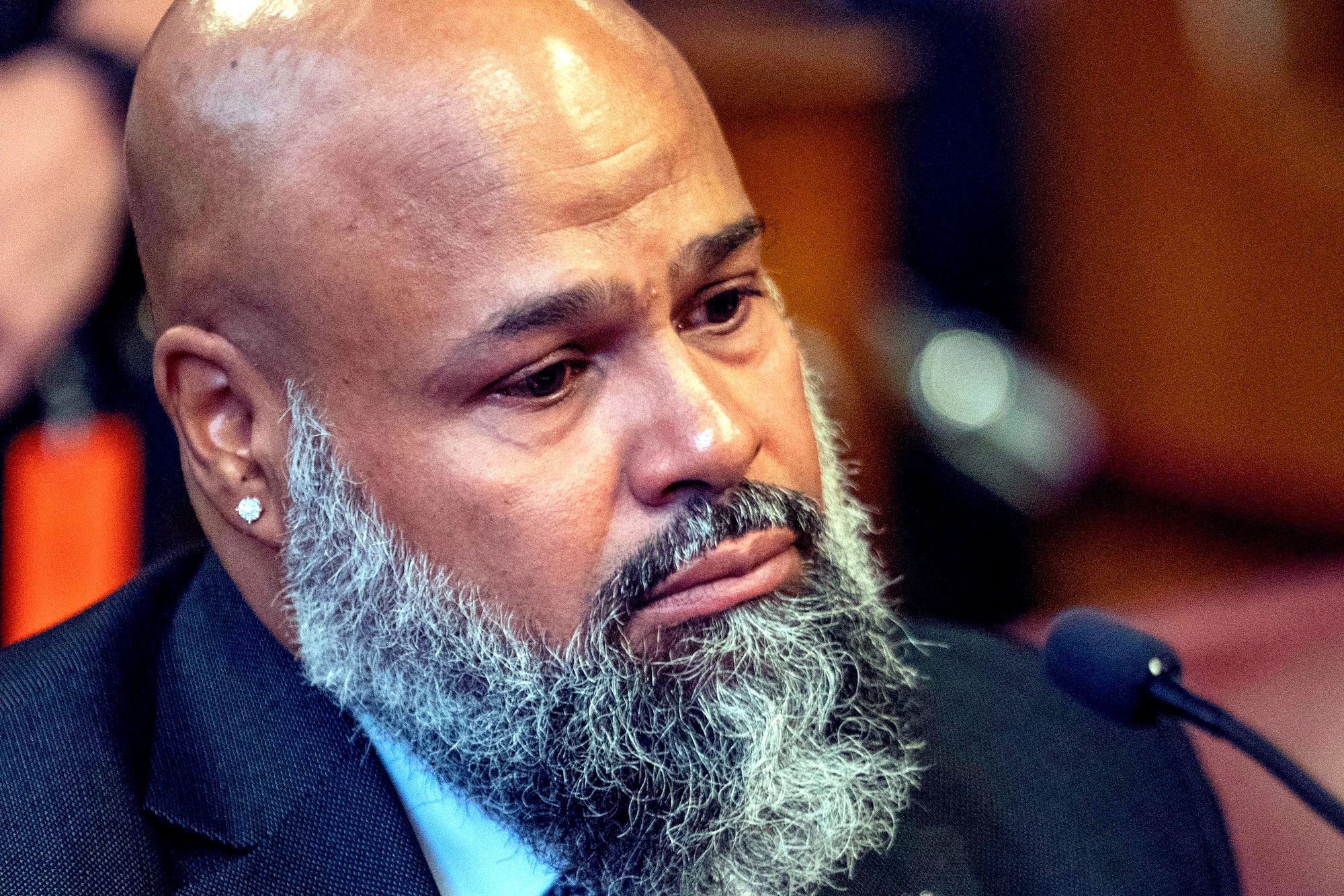 Steven Lopez, a 48-year-old man with medium-dark toned skin and wearing a suit, looks teary-eyed as he listens during a court hearing. 