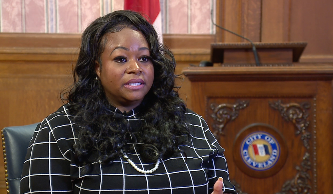 Leigh Anderson, a Black woman, sits in front of a podium. 