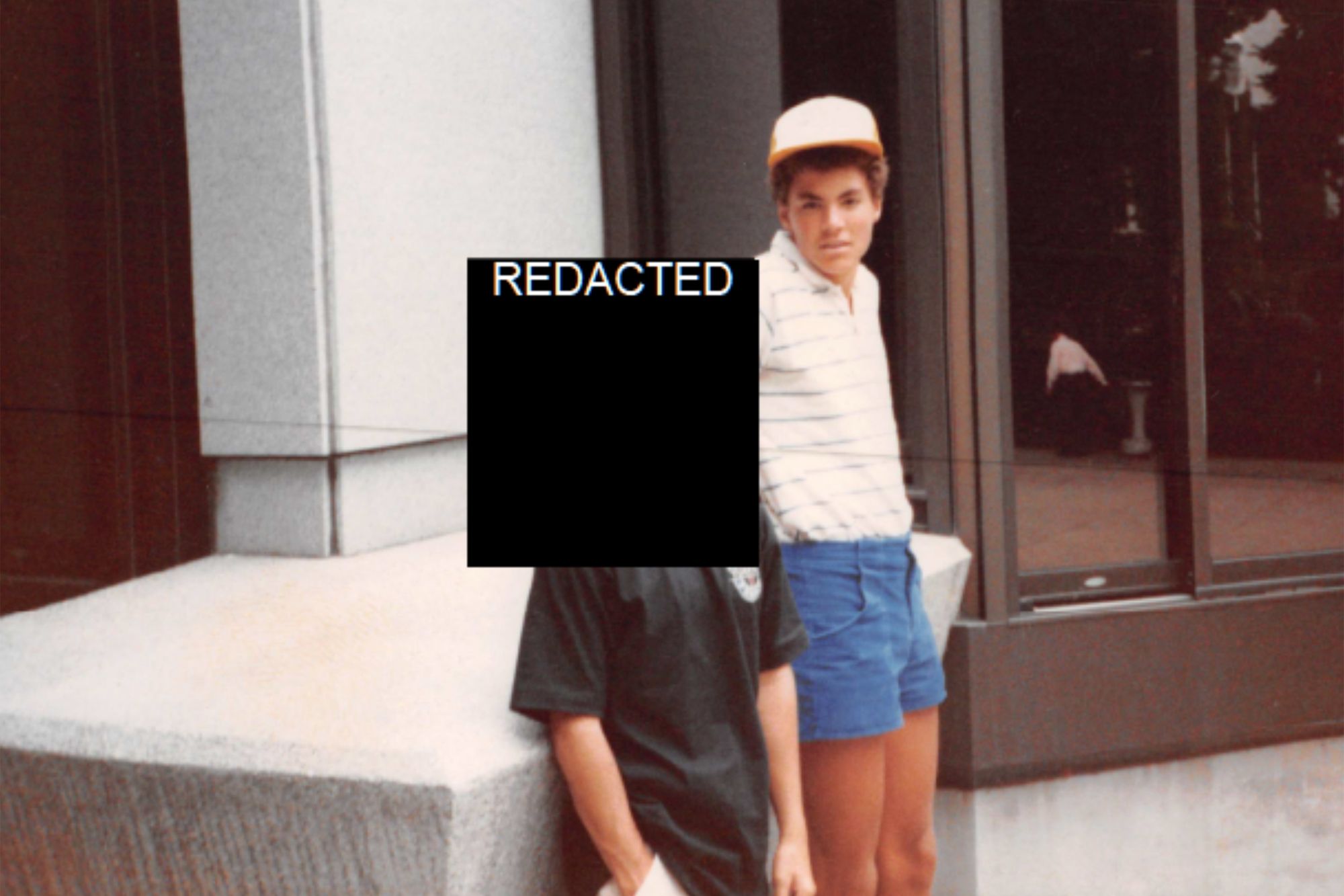 Jacob Wideman, a multiracial boy, wearing a striped white shirt, stands next to a person whose face is redacted. 