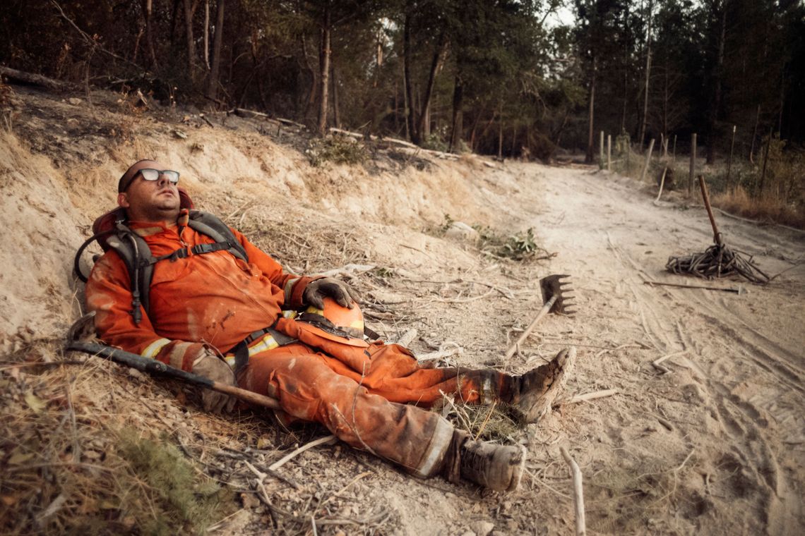 Eduardo Amezcua, exhausted from fighting wildfire in Sonoma County, takes a break on the side of a fire trail.