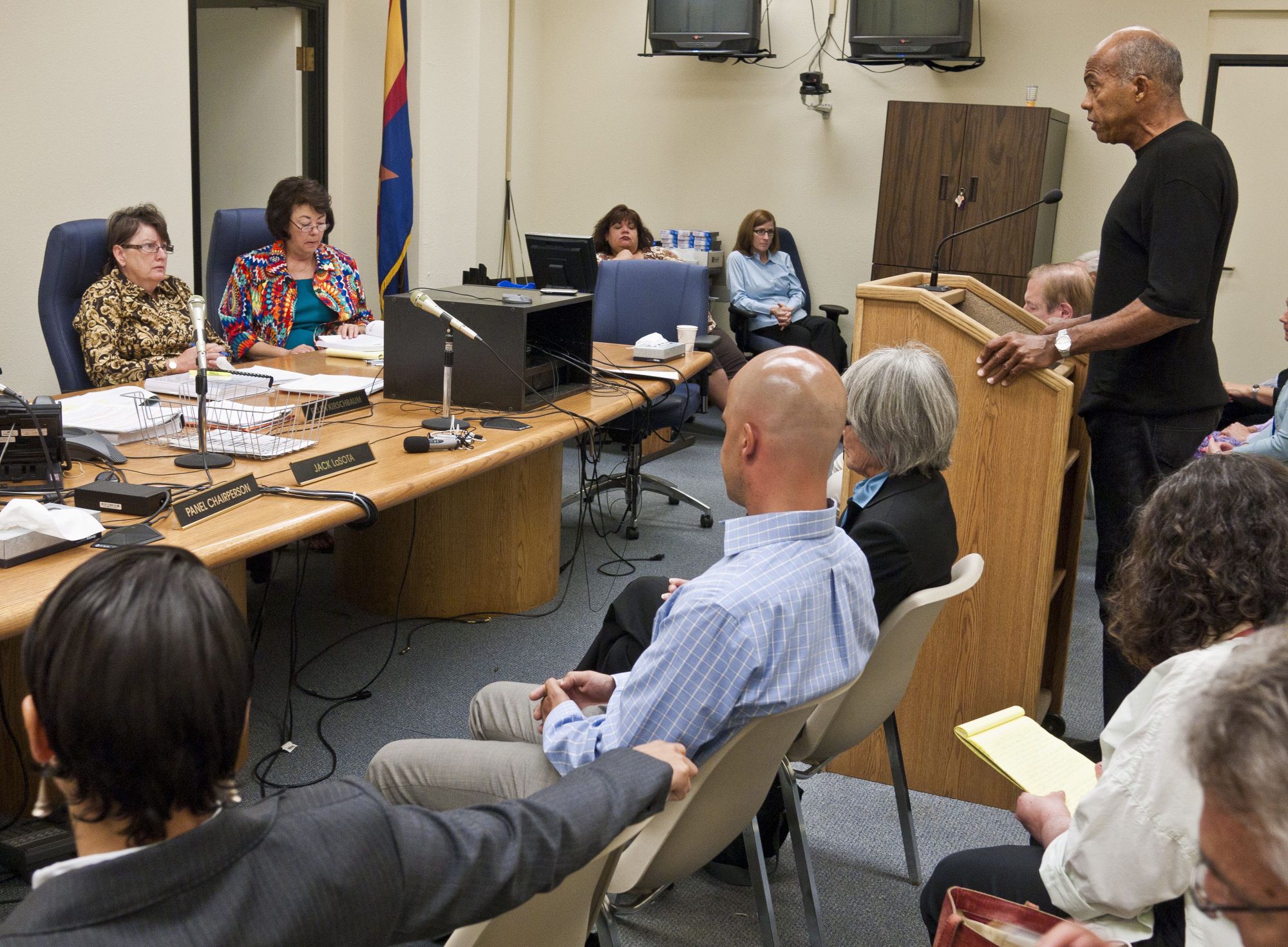 John Wideman, a Black man, spoke at a podium to a group of people in a meeting room.