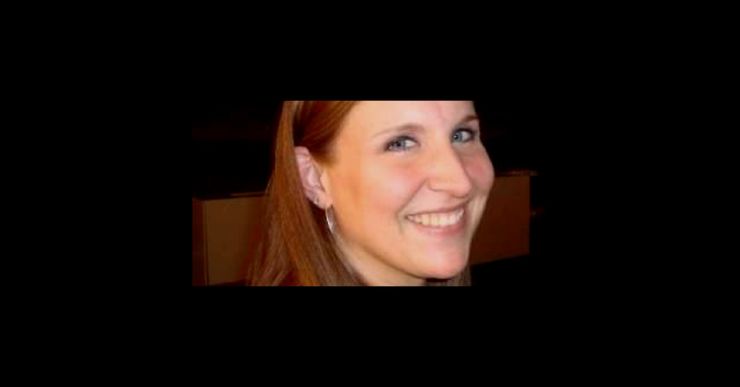 A White woman with long brown hair looks at the camera.  