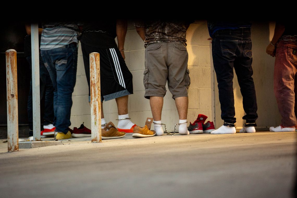 Migrants in shackles remove their shoes for a security check before they enter the federal courthouse in McAllen, Texas. They will be taken to a mass hearing where they will be prosecuted for illegal entry into the United States. 