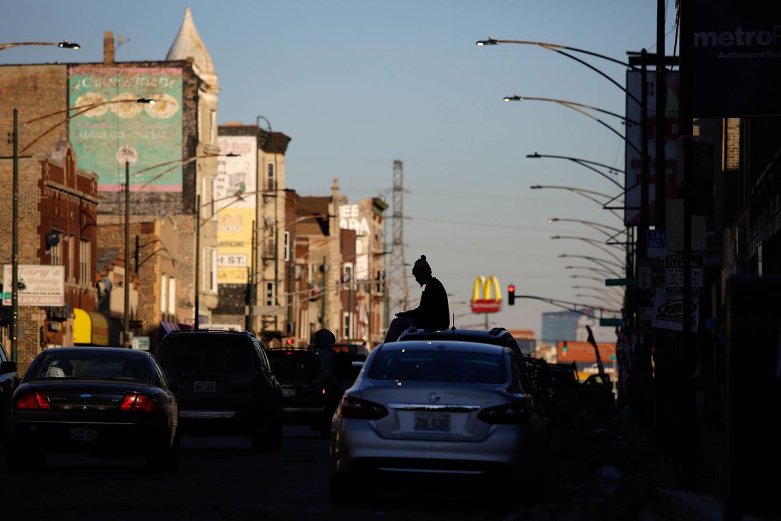 A man sits on top of a car on Cermak Road in Little Village.