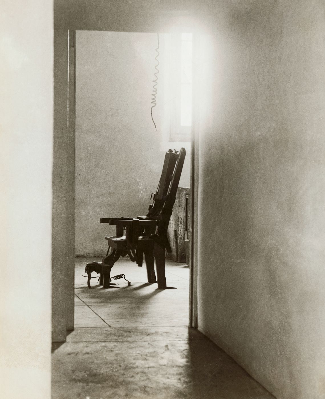 A black and white photo of an empty electric chair through a doorway. 