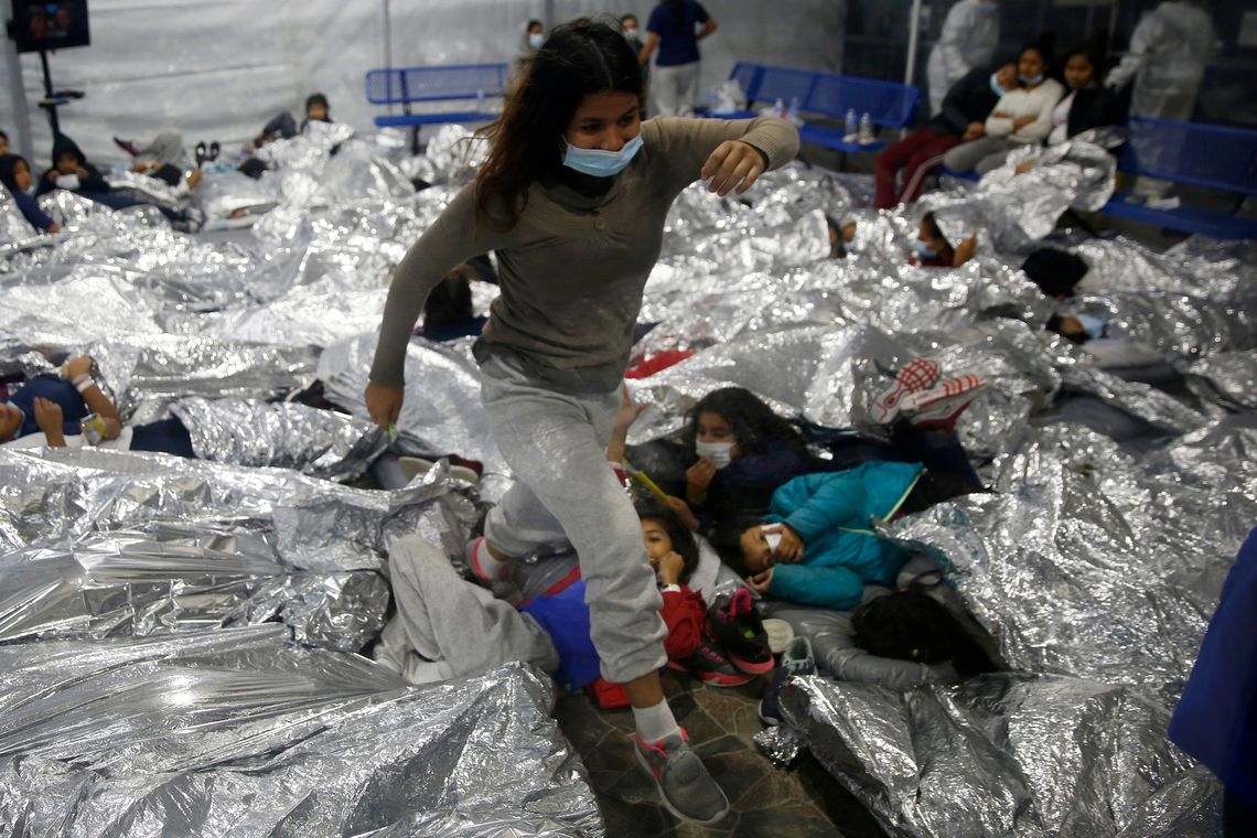 A young girl stepped over other children in a crowded cell for girls at the Customs and Border Protection holding facility in Donna, Texas, in March 2021. The children were housed in eight pods, each about 3,200 square feet, with many pods holding more than 500 children. The cell is similar to the one where M.J., a Guatemalan teenager, was held for 18 days.