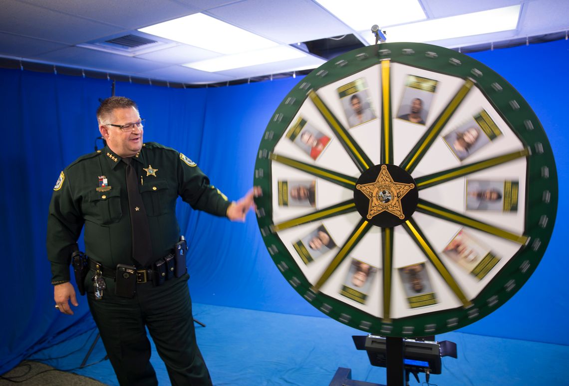 Sheriff Wayne Ivey of Brevard County spins the "Wheel of Fugitive" board inside the media studio at his office in 2017 in Titusville, Florida. 