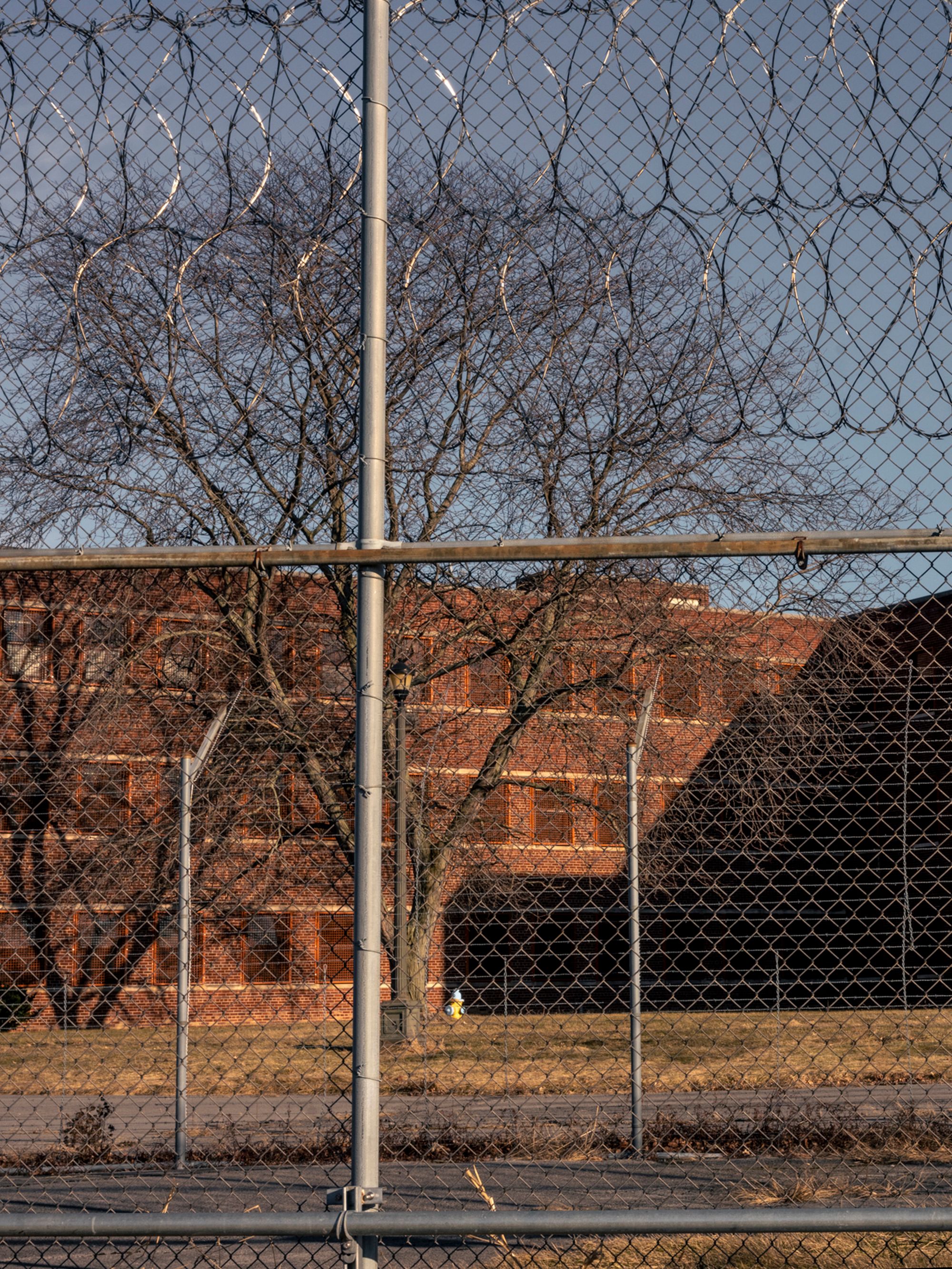 Willard Drug Treatment Center is made up of red brick, behind a barbed wire fence. 