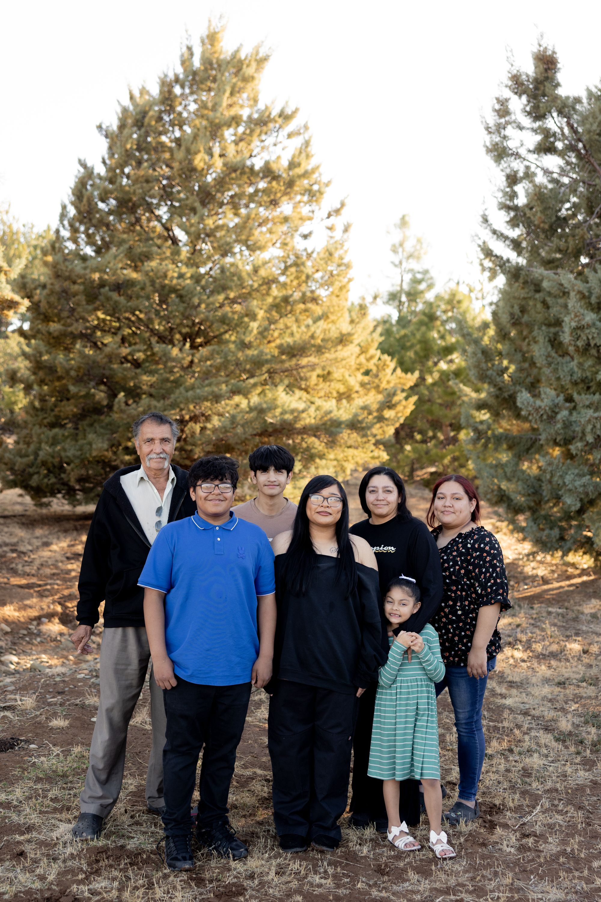 A photo shows a family of seven standing in a field, posing for a portrait together.