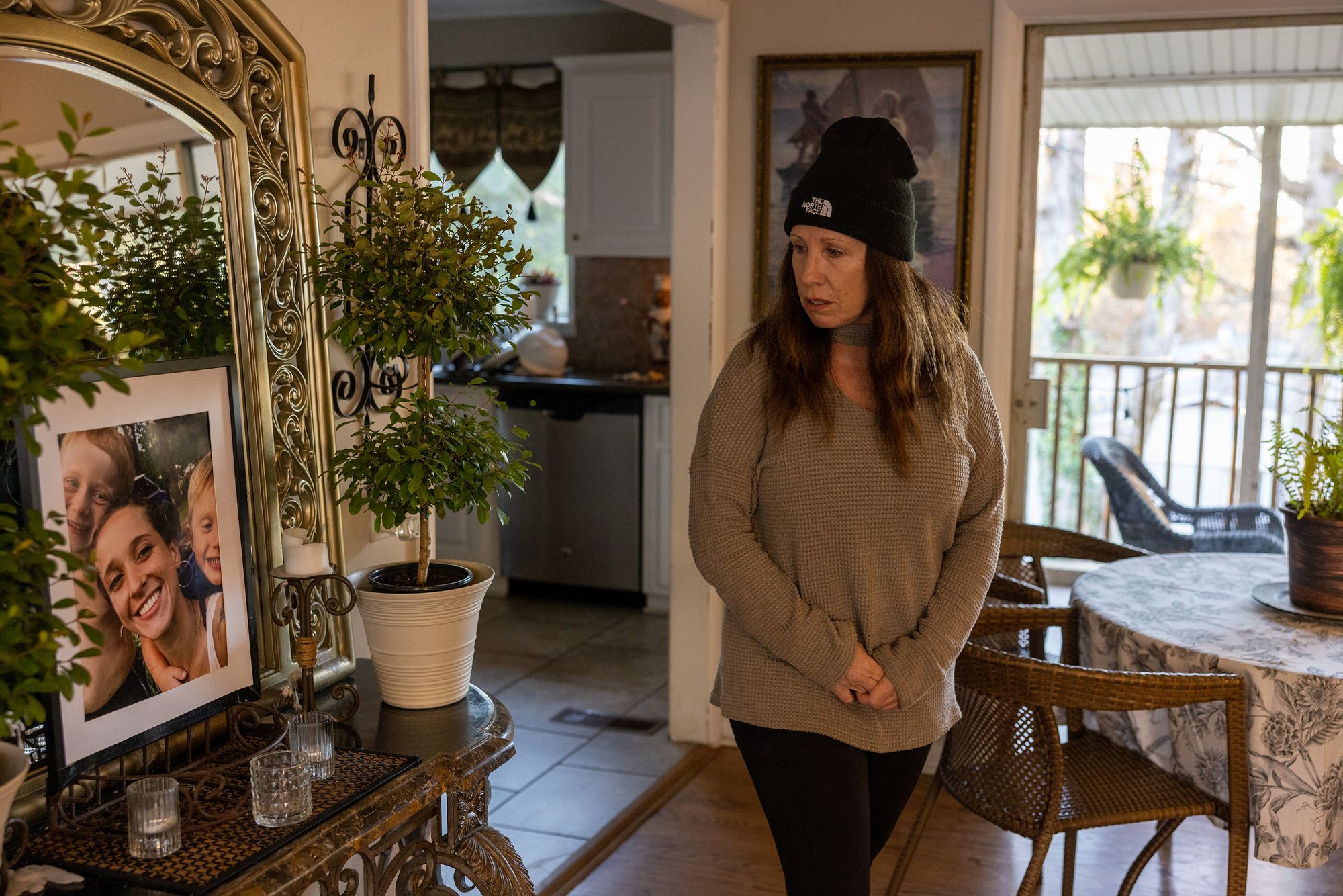 Michelle Helm walks by a family photo inside her Alabama home. Helm raised five children, including Tiara, after her husband died.