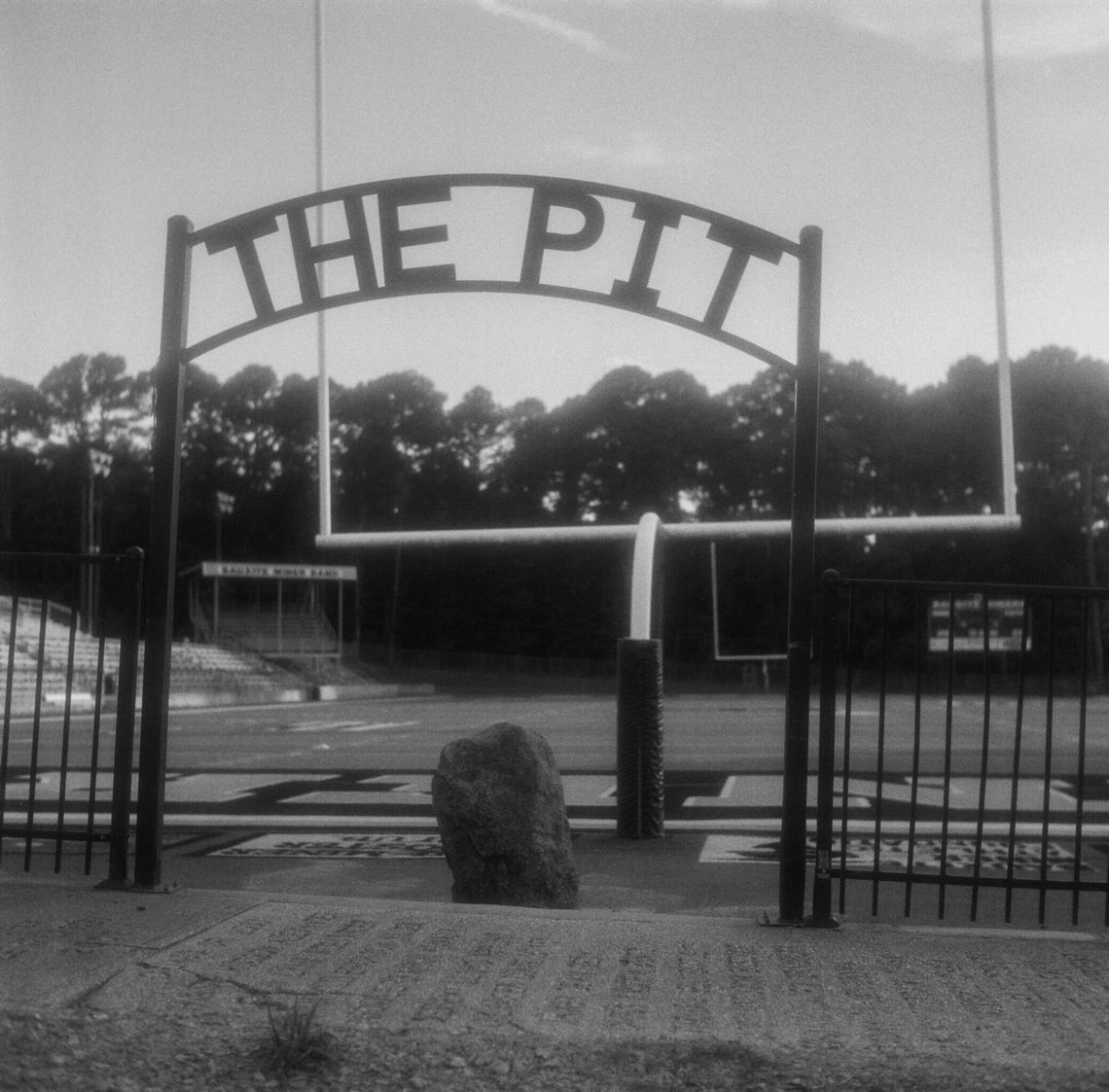 Three black-and-white photos show different views of a padded goalpost on a football field. 